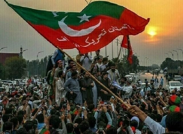 a pakistan tehreek e insaf pti supporter waves the party flag at a rally photo file