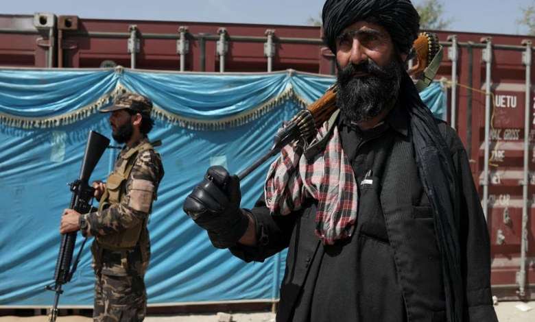 taliban fighters stand guard while people wait to receive sacks of rice as part of humanitarian aid sent by china at a distribution centre in kabul afghanistan april 7 2022 photo reuters